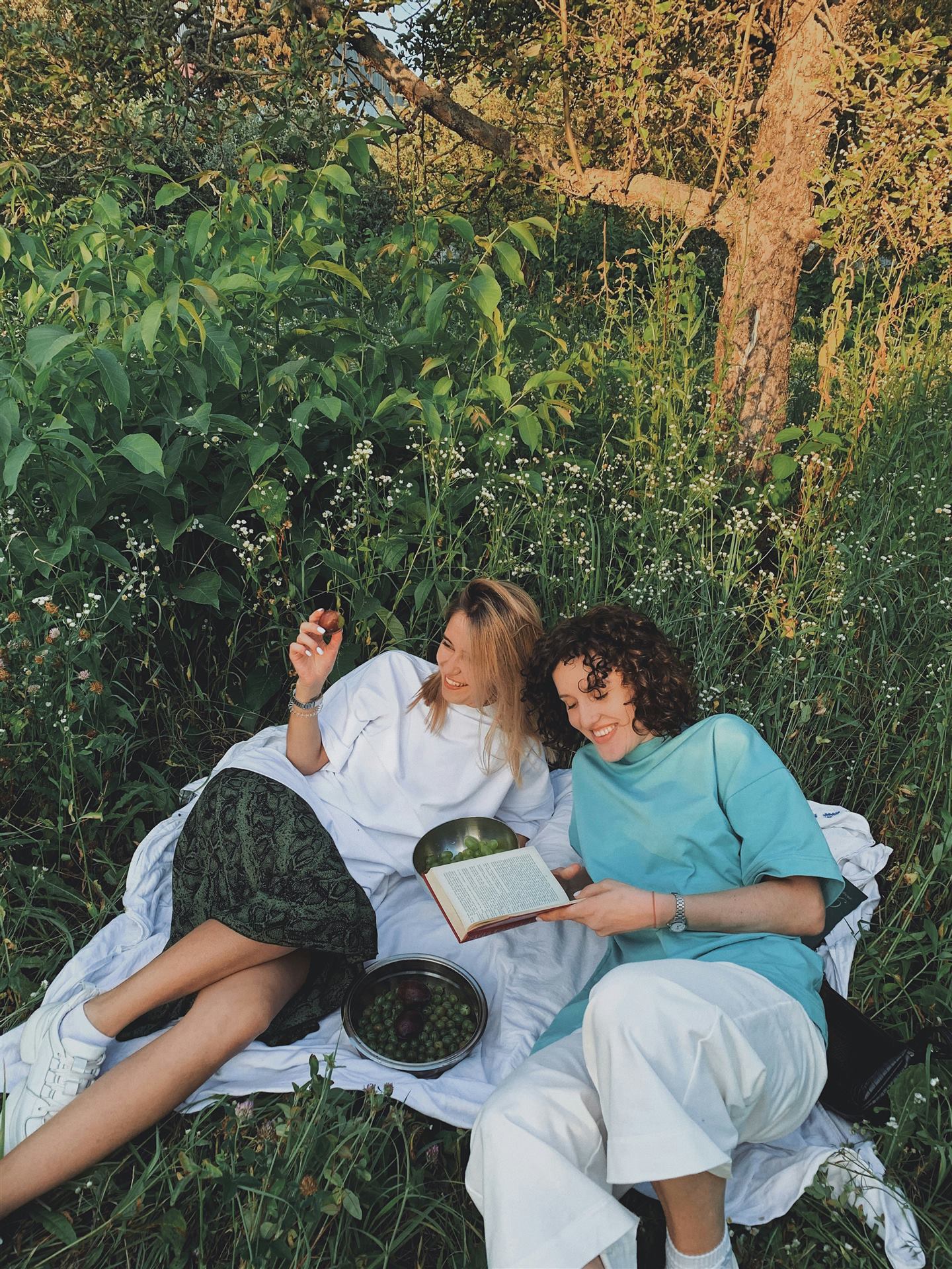 Amigas lendo um livro em um piquenique no gramado